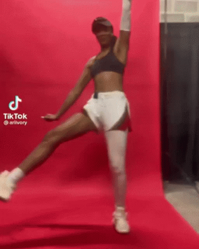 A Woman Is Standing On One Leg In Front Of A Pink Wall And A Pink Background . GIF