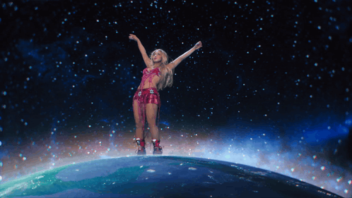 a woman is standing on top of a globe with her arms in the air