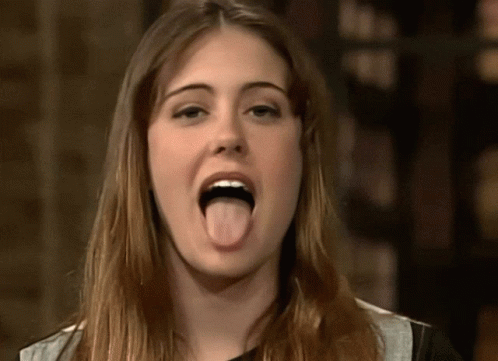 A Woman Is Sticking Her Tongue Out In A Close Up GIF