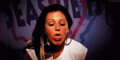 A Woman Is Sticking Her Tongue Out In Front Of A Sign That Says Pleasure Beach . GIF