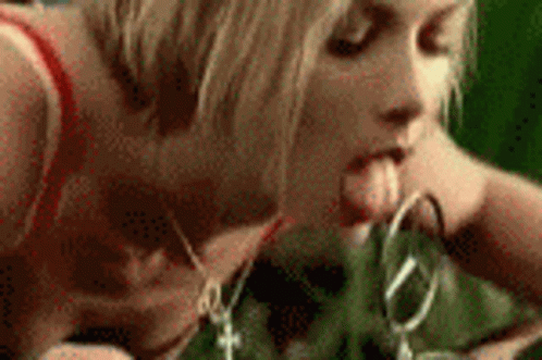 A Woman Is Sticking Her Tongue Out While Holding A Pair Of Scissors In Her Mouth . GIF