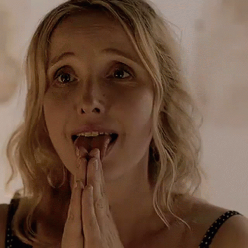 A Woman Is Sticking Her Tongue Out While Praying With Her Hands Together . GIF