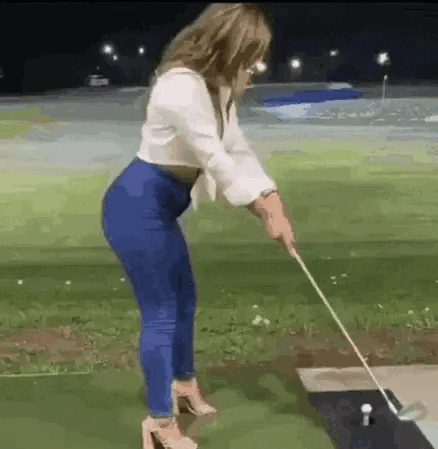 A Woman Is Swinging A Golf Club At A Golf Ball . GIF