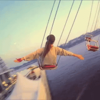 A Woman Is Swinging On A Merry Go Round At A Carnival GIF