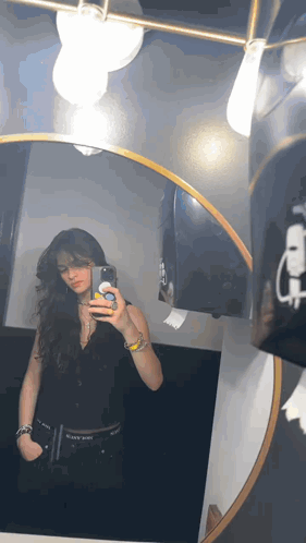 A Woman Is Taking A Selfie In A Bathroom Mirror With Her Phone . GIF