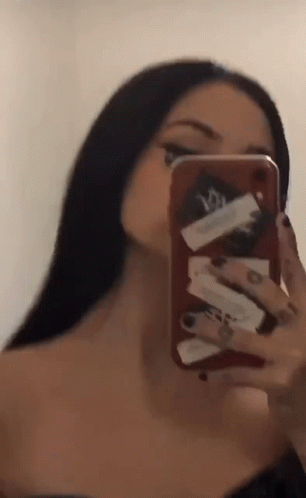 A Woman Is Taking A Selfie In The Mirror With Her Cell Phone . GIF