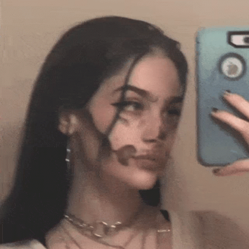 A Woman Is Taking A Selfie In The Mirror With Her Face Painted Black . GIF