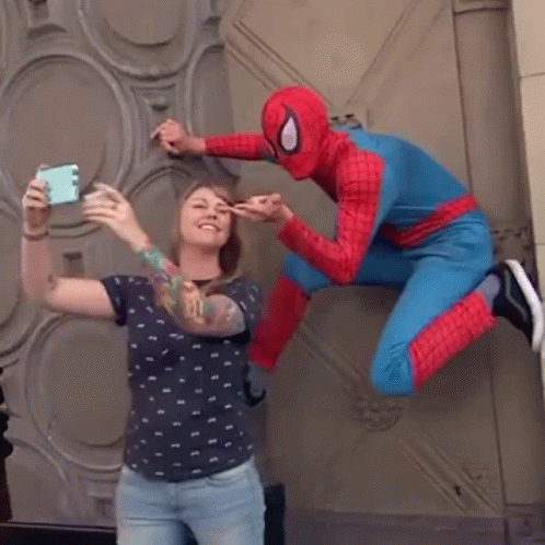 A Woman Is Taking A Selfie With A Spider Man In A Spiderman Costume GIF