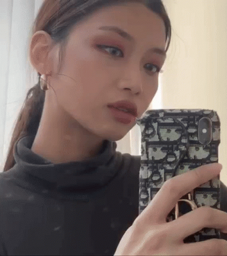 A Woman Is Taking A Selfie With Her Cell Phone . GIF