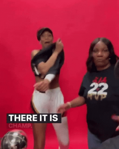 A Woman Is Taking Off Her Shirt While Standing Next To Another Woman In A Black Shirt With The Number 22 On It . GIF