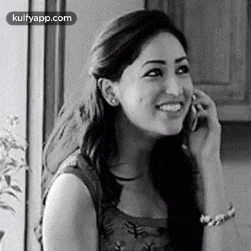 A Woman Is Talking On A Cell Phone And Smiling . GIF