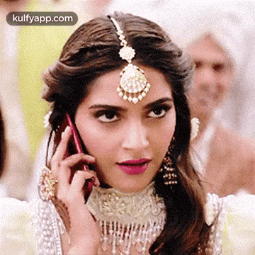 A Woman Is Talking On A Cell Phone While Wearing A Headpiece . GIF