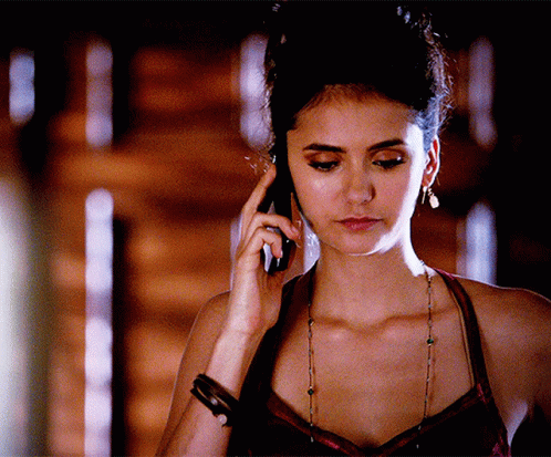 A Woman Is Talking On A Cell Phone With A Cigarette In Her Mouth GIF