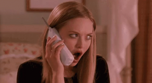 A Woman Is Talking On A Cell Phone With Her Mouth Open And Making A Surprised Face . GIF