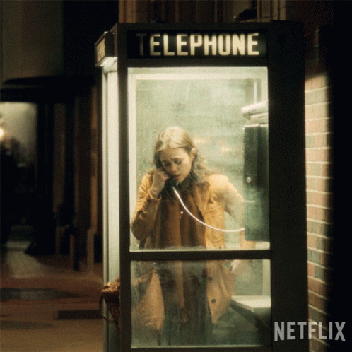 A Woman Is Talking On A Phone In A Telephone Booth With Netflix Written On The Bottom GIF