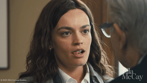 A Woman Is Talking To A Man With Ella Mccay Written On The Bottom GIF