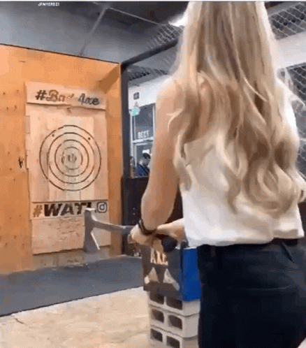 A Woman Is Throwing An Axe At A Target That Says #Bad Axe GIF