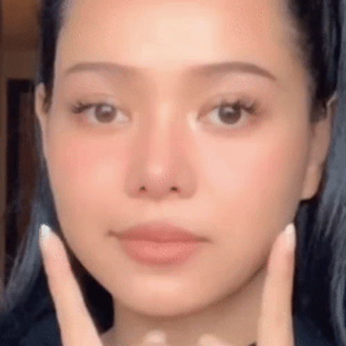 A Woman Is Touching Her Face With Her Hands . GIF