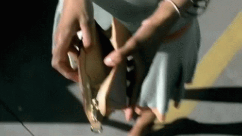 Woman Tying Shoes In Parking Lot Wearing Skirt GIF