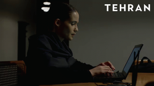 A Woman Is Typing On A Laptop With Tehran In White Letters GIF