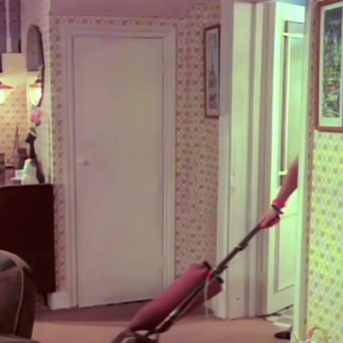 A Woman Is Using A Vacuum Cleaner In A Room GIF