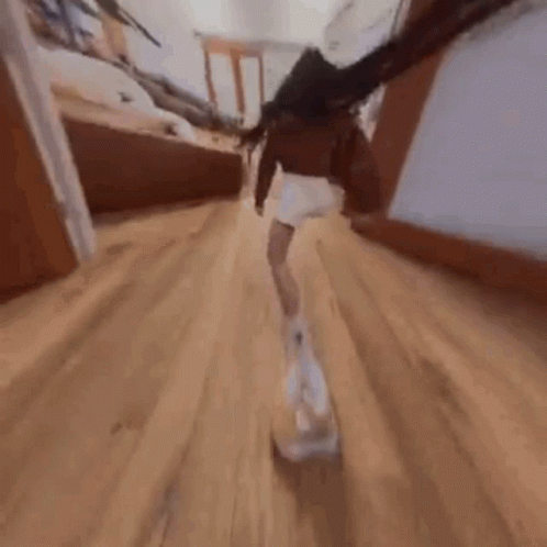 A Woman Is Walking Down A Hallway With A Dog In Her Hand . GIF