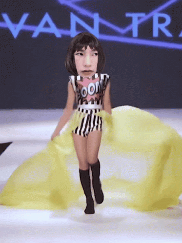 A Woman Is Walking Down A Runway With A Vanity Fair Logo Behind Her GIF