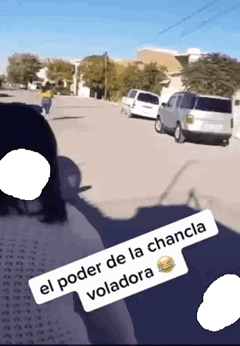 a woman is walking down a street with a sign that says el poder de la chancla voladora
