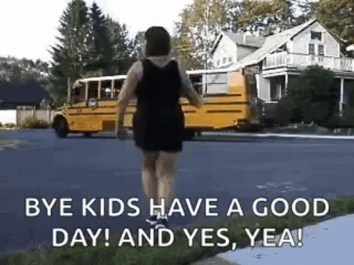 A Woman Is Walking Down The Street In Front Of A School Bus . GIF