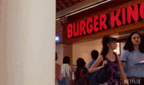 A Woman Is Walking In Front Of A Burger King Restaurant . GIF