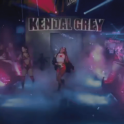 a woman is walking on a stage in front of a sign that says kendall grey .