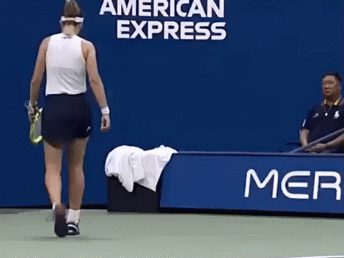 A Woman Is Walking On A Tennis Court In Front Of A Banner That Says American Express GIF