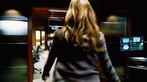 A Woman Is Walking Through A Room With A Lot Of Monitors . GIF