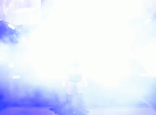 A Woman Is Walking Through A Tunnel Of Smoke And Lights GIF