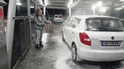 A Woman Is Washing A White Skoda Car With A License Plate That Says Aa-118-Vv GIF