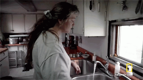 A Woman Is Washing Her Hands In A Kitchen Sink With Natgeotv.com Written On The Bottom GIF