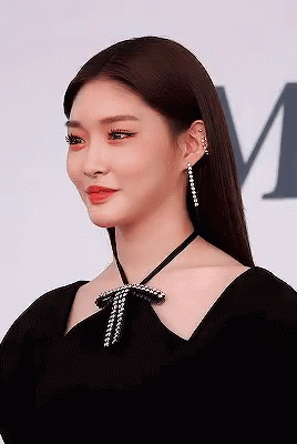 A Woman Is Wearing A Black Dress And Earrings . GIF