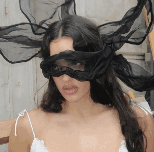 A Woman Is Wearing A Black Mask On Her Eyes GIF