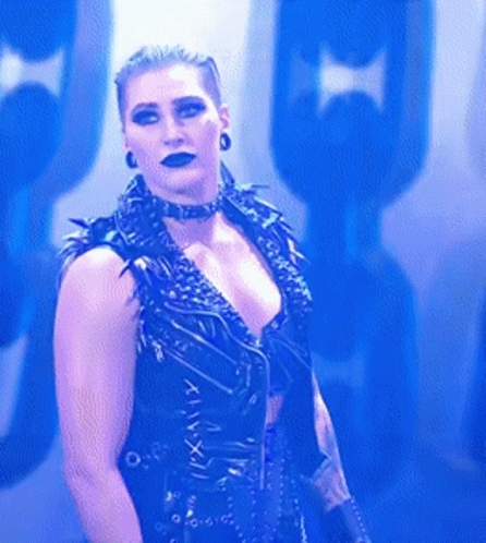 A Woman Is Wearing A Choker And A Black Vest With Roman Numerals On The Front . GIF