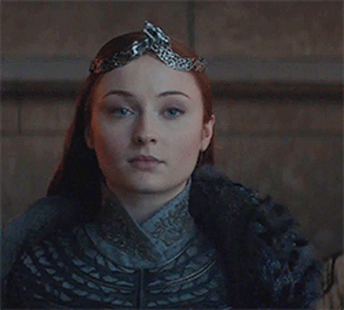 A Woman Is Wearing A Crown On Her Head And Looking At The Camera . GIF