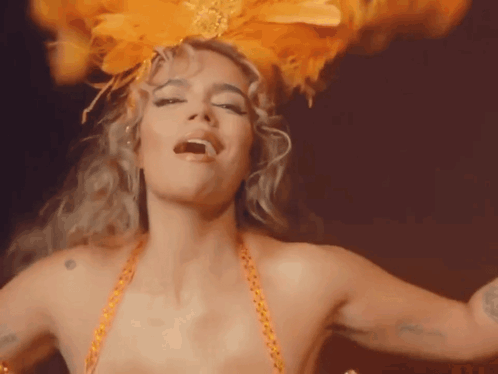 A Woman Is Wearing A Feathered Headpiece And Dancing GIF