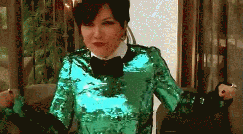 A Woman Is Wearing A Green Sequined Top And A Black Bow Tie GIF