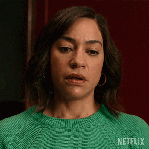 A Woman Is Wearing A Green Sweater With Netflix Written On It GIF