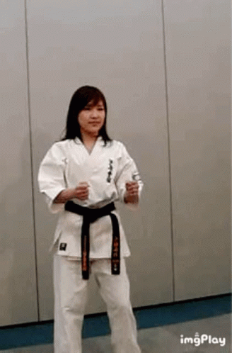 A Woman Is Wearing A Karate Uniform And A Black Belt . GIF