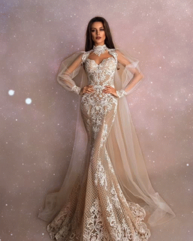 A Woman Is Wearing A Long White Dress With A Cape GIF