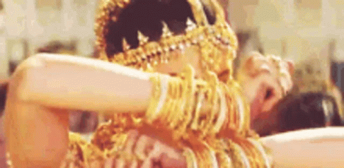 A Woman Is Wearing A Lot Of Gold Jewelry And Dancing . GIF