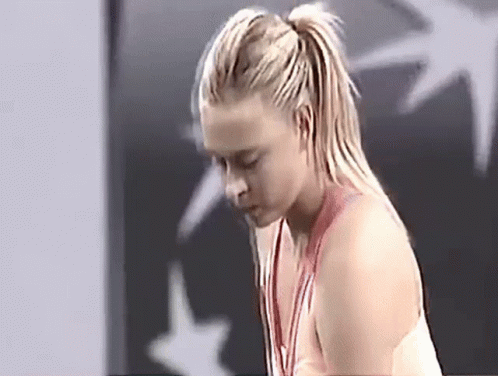 A Woman Is Wearing A Medal Around Her Neck And Looking Down GIF
