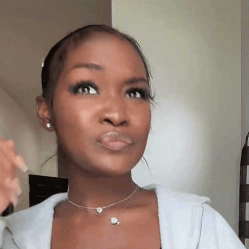 A Woman Is Wearing A Necklace And Earrings And Making A Face . GIF