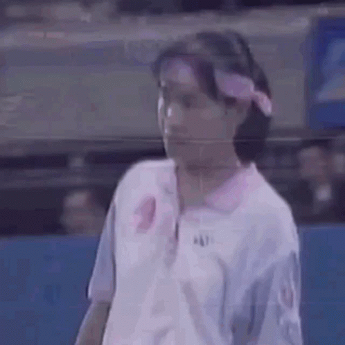 A Woman Is Wearing A Pink Headband And A White Shirt . GIF