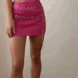 A Woman Is Wearing A Pink Skirt And A Chain Belt . GIF